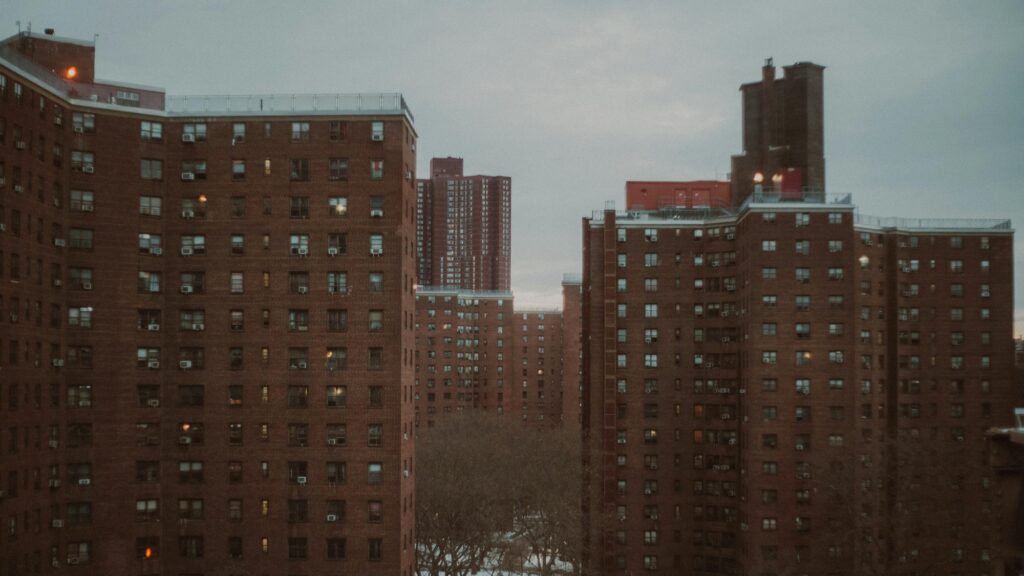 NYCHA red-brick high-rise towers with rooftop safety fencing in New York City during winter